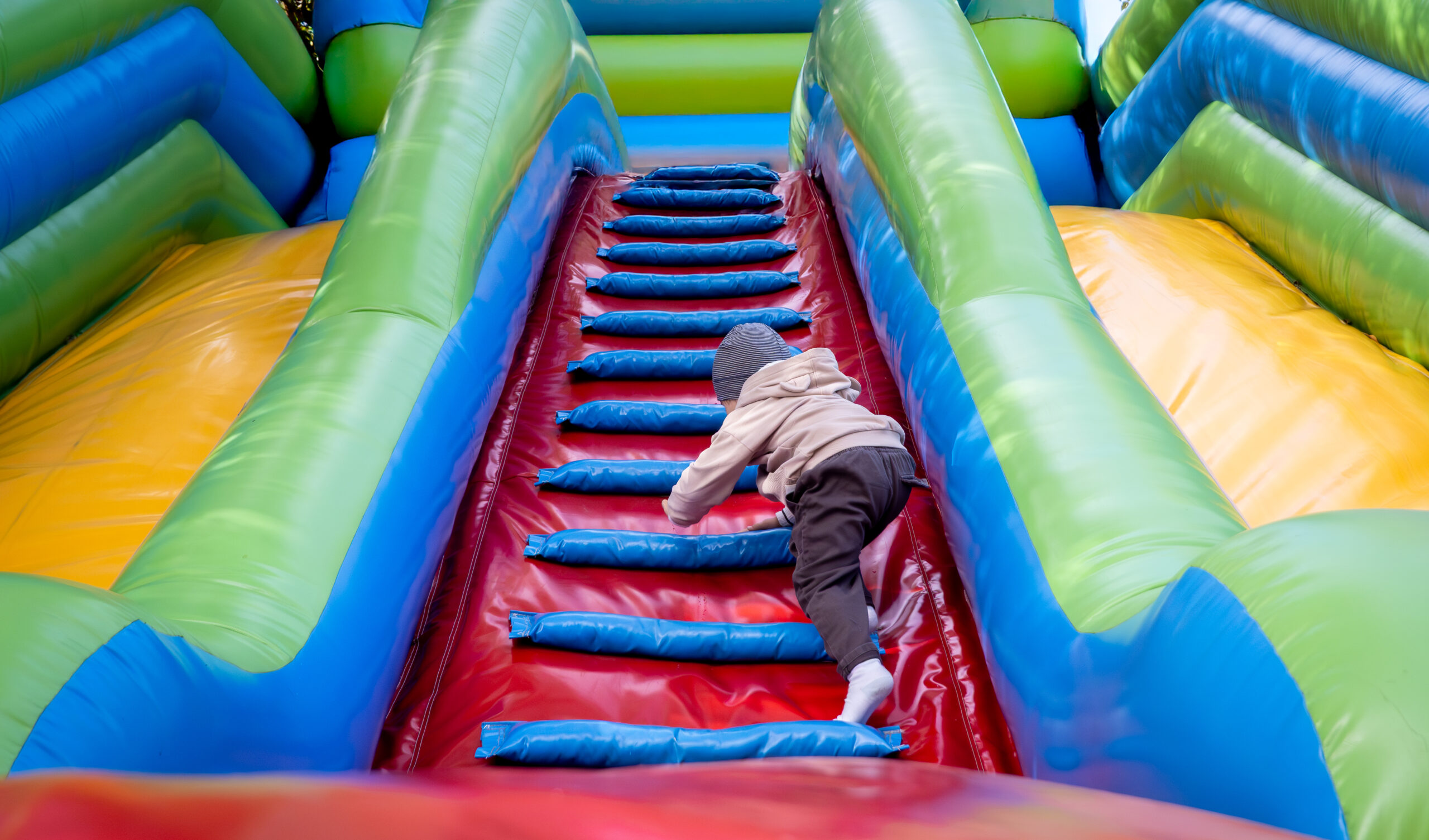 Boy climbs onto a large inflatable slide to go down